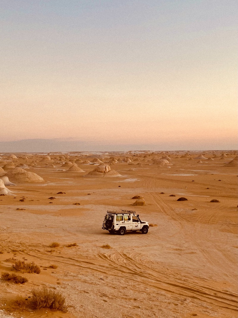 A white truck in an orange tinted desert.