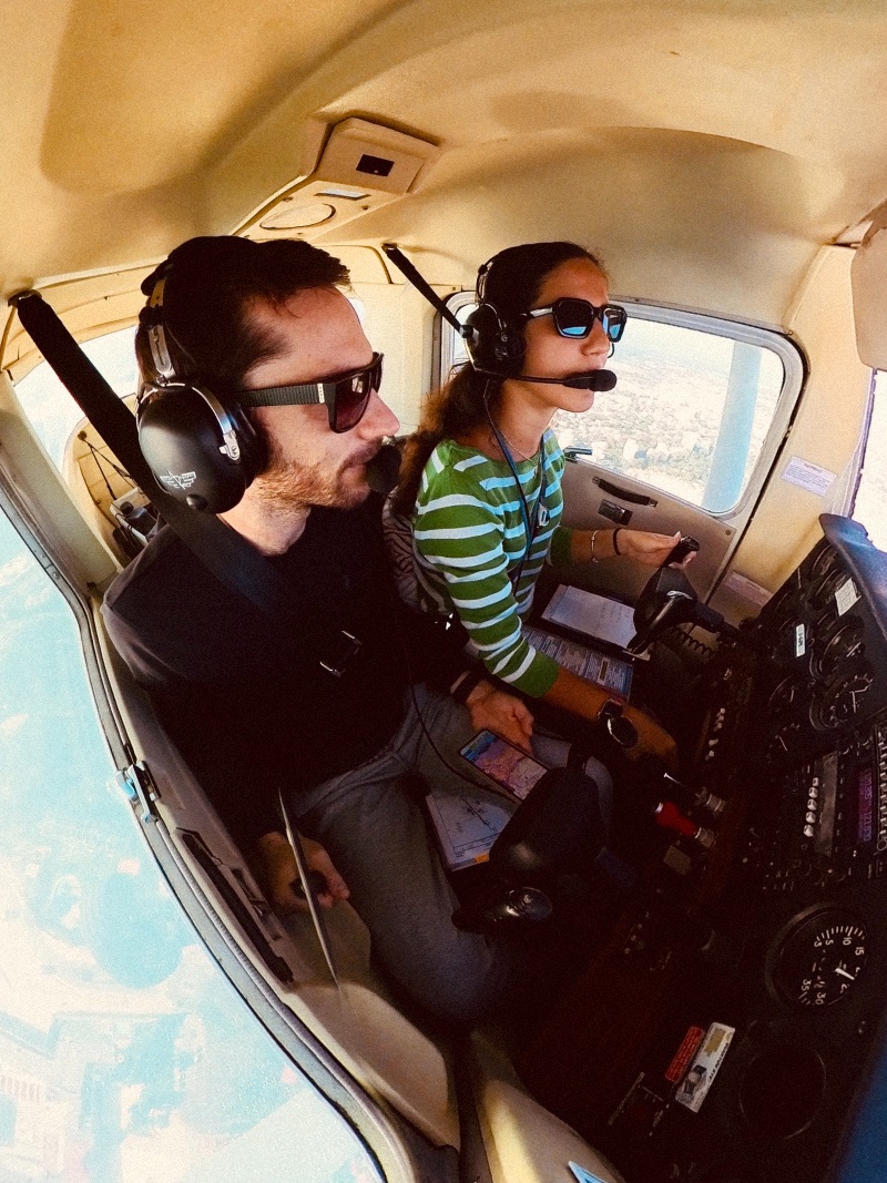 A woman flying a Cesna plane with a man as the passenger looking out the window.