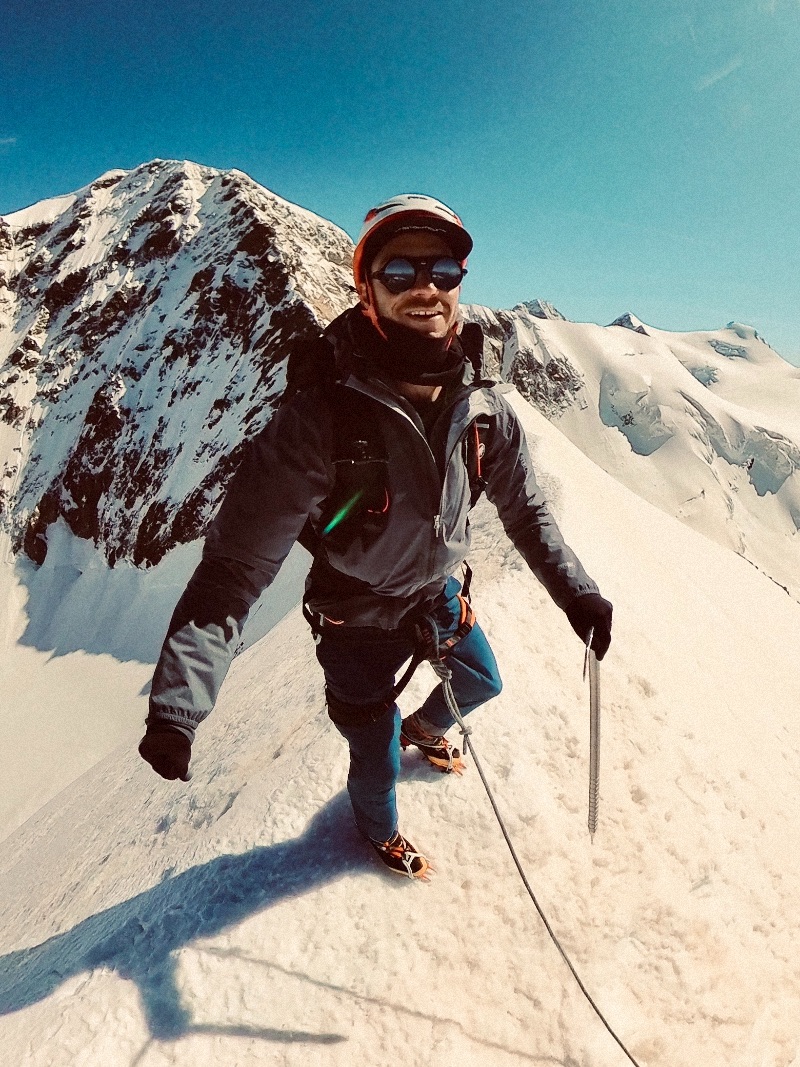 A man standing on top of a snowy mountain peak holding an ice axe.